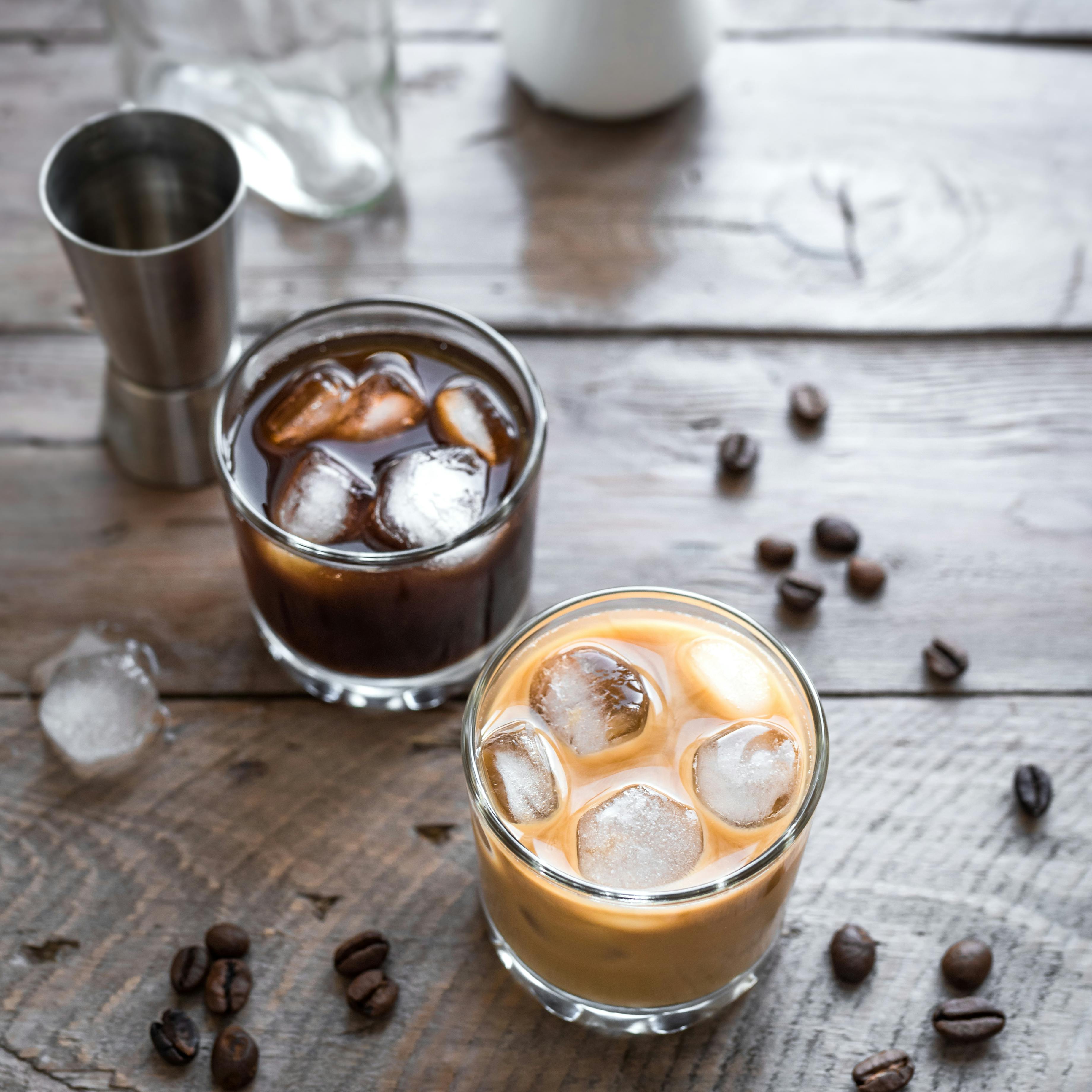 Black and White Russian Cocktails with Vodka, Coffee Liquor and Cream. Homemade iced Alcohol Boozy Black Russian and White Russian drink with coffee beans on wooden background, copy space.