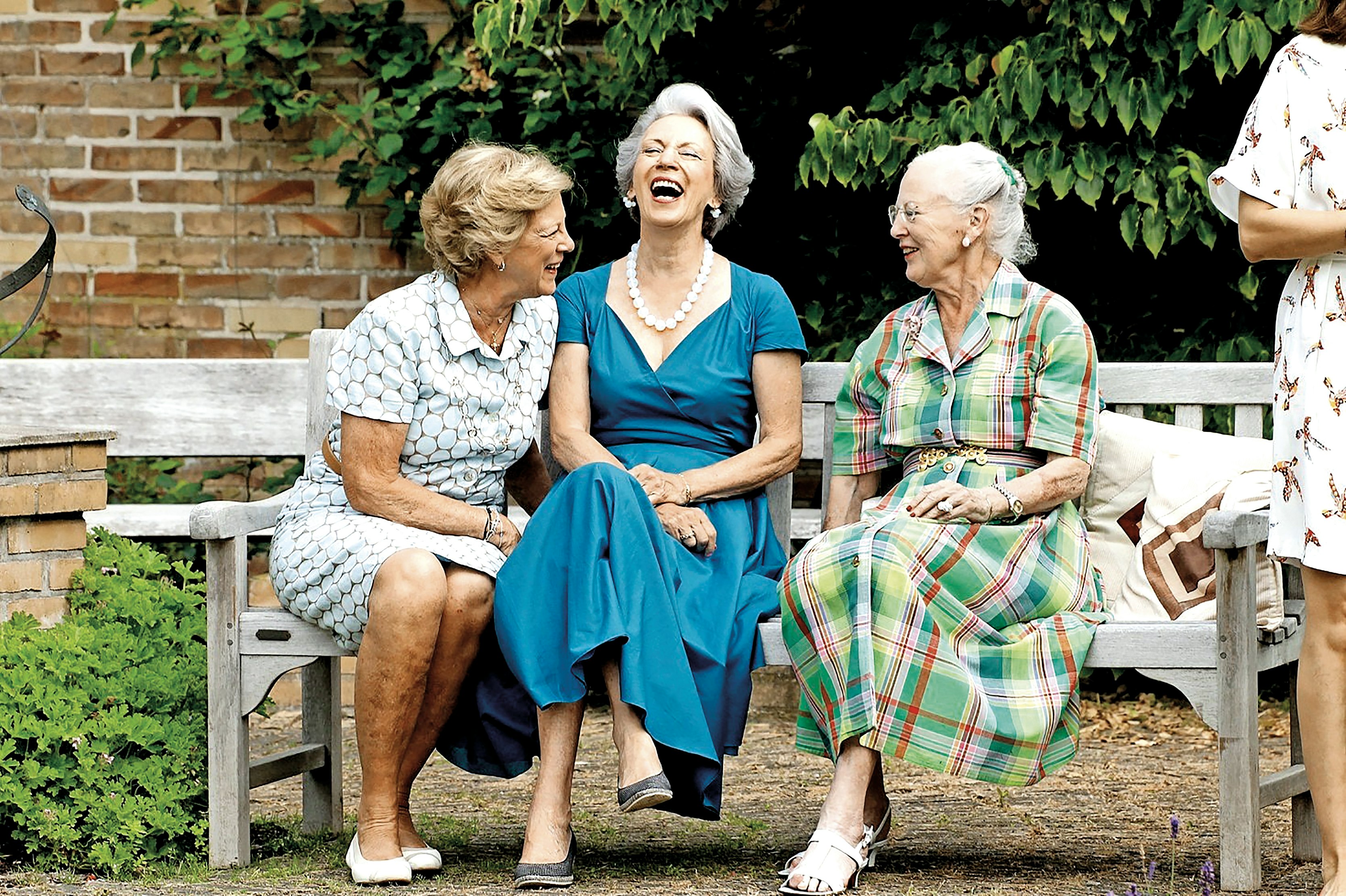 Dronningen sidder på en bænk med sine søstre Benedikte og Anne-Marie