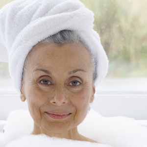 Kvinde i badekar med håndklæde om håret