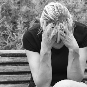 Deprimeret moden kvinde i sort hvid på bænk udenfor