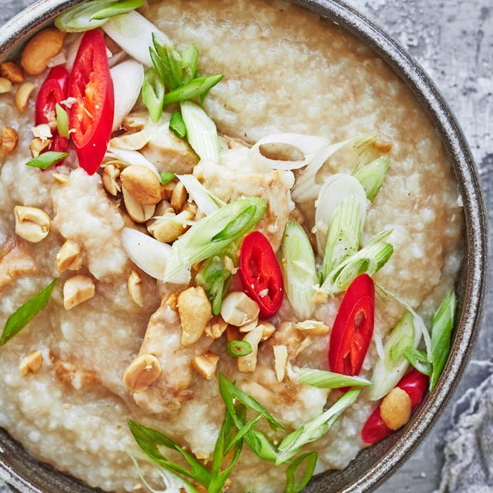 Congee med soyastegt kylling og toppet med chili, forårsløg og peanuts