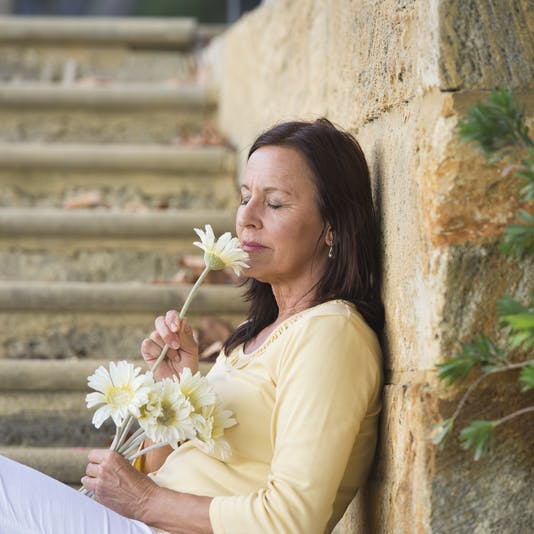 En kvinde der dufter til en blomst - sanser