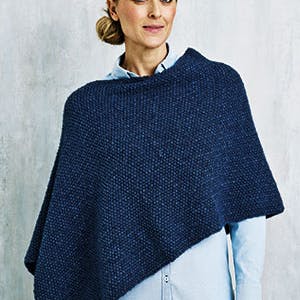 Kvinde i mørkeblå strikket poncho - gratis strikkeopskrift