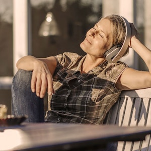 Kvinde der lytter til musik eller podcast i solen 