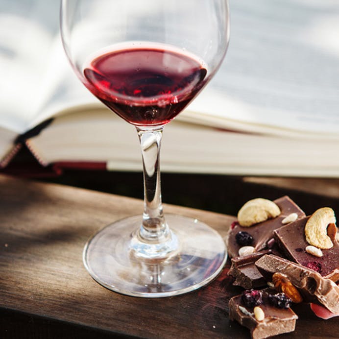 Rødvin, chokolade og nødder på et bord 
